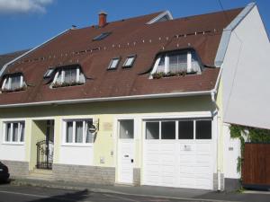 ein Haus mit weißen Türen und einem braunen Dach in der Unterkunft Kántor Vendégház in Zalaegerszeg