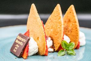 drei Sandwiches mit Schlagsahne und Erdbeeren auf einem Teller in der Unterkunft Hotel Petrarca in Boara Pisani