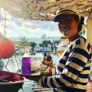 a man holding a tray of food on the water at The Oia Pai Resort in Pai