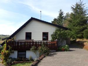une maison blanche avec une terrasse dans une allée. dans l'établissement Ferienhaus ROSENHOF Vulkaneifel, à Ormont