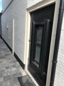 una porta nera sul lato di un edificio di Thomasloft a Oegstgeest