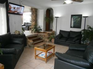 sala de estar con sofás de cuero negro y mesa en Hotel Lihuel en Villa Carlos Paz