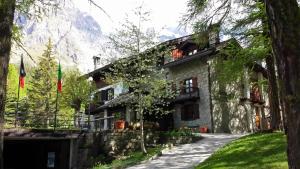 une maison en pierre avec une montagne en arrière-plan dans l'établissement Hotel Locanda Belvedere, à Courmayeur