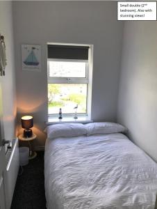 a white bedroom with a bed and a window at Apt3, 2 Antrim Gardens, Portrush with Seaview in Portrush