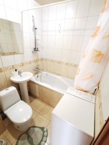 a bathroom with a toilet and a sink and a tub at Lavina mall apartments 4 in Sumy