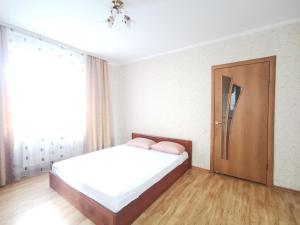 a white bedroom with a bed and a window at Lavina mall apartments 4 in Sumy