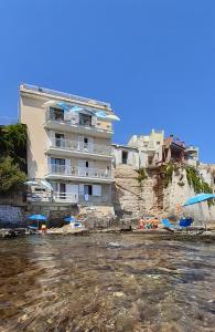 un gran edificio en la playa con sillas y sombrillas en Giuggiulena, en Siracusa