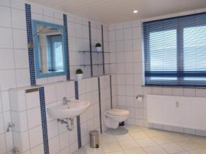 a white tiled bathroom with a sink and a toilet at Ferienwohnung Knobloch in Wahlheim