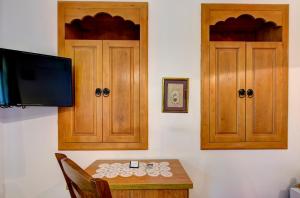 a room with a table with a tv and wooden cabinets at Hotel Almira in Mostar