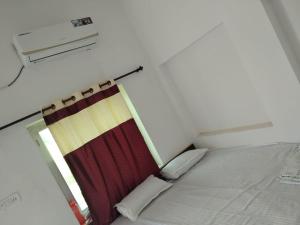 a bed in a room with a red curtain at Aashirwad Garden & Resort in Pilani