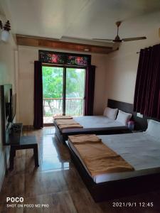 a room with three beds and a window at NANDANVAN TENT & RESORT TAPOLA in Medha