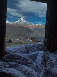 a bed with a view of a snow covered mountain at Kazbegi Twins in Stepantsminda