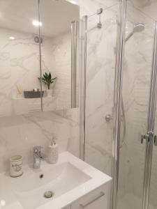 La salle de bains blanche est pourvue d'une douche et d'un lavabo. dans l'établissement Romos apartamentai Klaipėdoje, à Klaipėda