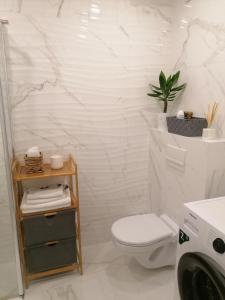 La salle de bains blanche est pourvue de toilettes et d'une plante. dans l'établissement Romos apartamentai Klaipėdoje, à Klaipėda