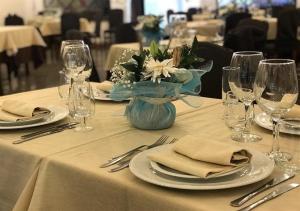 a table with plates and glasses and a vase of flowers at Ahm7nani in Mascali