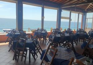 een eetkamer met tafels en stoelen en de oceaan bij Ahm7nani in Mascali