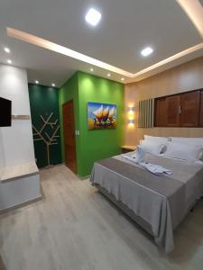 a bedroom with a large bed and a green wall at Chalés Pedra da Pipa in Pipa