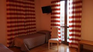 a room with a bed and a chair and a window at Le Querce Hotel in Salsomaggiore Terme