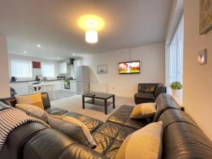 a living room with a leather couch and a kitchen at Moor View Professional Let in Durham