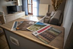 En la sala de estar hay una mesa con revistas y periódicos. en Residenza Zoia en Sondrio
