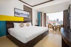 a bedroom with a large bed and a desk and a room at Thanh Lan Riverside Hotel Da Nang in Danang