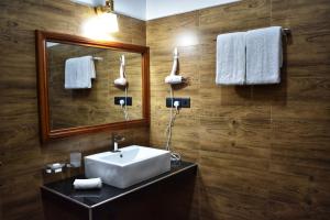 un bagno con lavandino, specchio e asciugamani di Forest Edge Safari Villa a Udawalawe