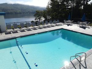 a large swimming pool with chairs and a lake at Lakefront Terrace Resort in Lake George