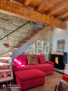 ein Wohnzimmer mit einem roten Sofa und einer Steinmauer in der Unterkunft Romantico Chalet in pietra da mille e una notte in Petralia Soprana