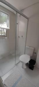 a white bathroom with a toilet and a shower at Apartamento Ponta do Papagaio - Térreo in Palhoça +13 photos