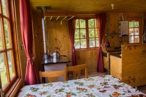 Habitación con mesa y cocina con ventanas. en Refugio La Rinconada, en Bahía Murta