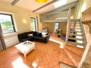 a living room with a couch and a staircase at LA BERGERIE DU DAMIAN in Neuville