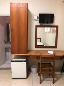 a bathroom with a desk with a mirror and a cabinet at Regio Plaza Hotel in Ourinhos