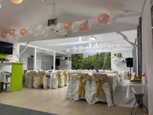 una sala banchetti con tavoli bianchi con palloncini e archi di Complex Turistic Dávid a Boghiş Altre 37 foto
