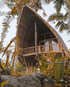 a bamboo house on the water with palm trees at Jero Tumbuk Private Villa in Selat