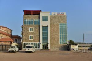 un bâtiment avec deux voitures garées devant lui dans l'établissement RED SEA HOTEL APARTMENT, à Djibouti