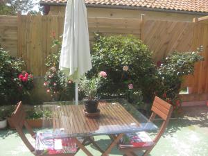 - une table de patio avec un parasol et deux chaises dans l'établissement karine, à Boucau