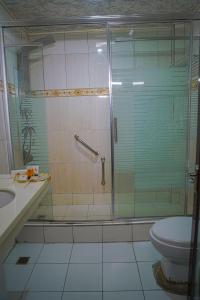 a bathroom with a shower with a toilet and a sink at Metro Hotel Couva in Couva