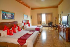 a hotel room with two beds and a flat screen tv at Metro Hotel Couva in Couva