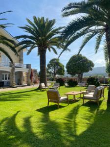a park with benches and palm trees in front of a building at Hotel Regueiro in Tox