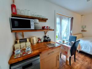 cocina con escritorio, microondas y cama en Cosy Snug with shower ensuite - It has beautiful countryside views - Only 3 miles from Lyme Regis, Charmouth and River Cottage - It has a private balcony and a real open fireplace - Comes with free private parking, en Axminster