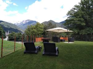 zwei Stühle und ein Regenschirm auf einem Rasen mit Bergen in der Unterkunft Alpenrooms in Transacqua