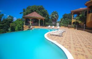 ein Swimmingpool mit Stühlen und einem Pavillon in der Unterkunft Luxury 10 Bedroom Villa-Millbrooks in Montego Bay