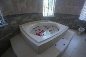 eine Badewanne mit roten Blumen im Bad in der Unterkunft Luxury 10 Bedroom Villa-Millbrooks in Montego Bay