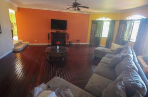 ein Wohnzimmer mit Sofa und Fernseher in der Unterkunft Luxury 10 Bedroom Villa-Millbrooks in Montego Bay