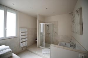 a white bathroom with a shower and a tub at La Villa Paris - B&B in Paris