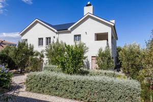 a white house with bushes in front of it at Nerf-af Cottage and private ROOMs at Onrus , Hermanus in Hermanus