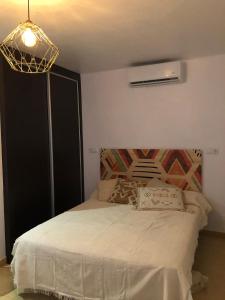 a bedroom with a bed and a chandelier at Apartmento studio boho a 1 minuto del puerto y la playa! in Jávea
