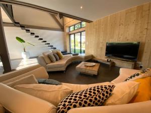 CHEZ LE DAMIAN في Neuville: غرفة معيشة مع كنب وتلفزيون بشاشة مسطحة