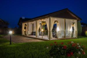 un cenador con cortinas blancas en un patio por la noche en Hostynnyy Dvir en Stryi