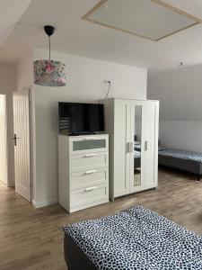 a bedroom with a bed and a dresser with a television at Hanuszówka pokoje gościnne z łazienkami in Nysa